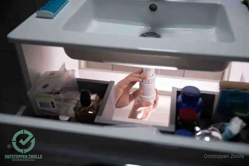 Een pompfles met zeep boven een wastafel, de heet water en afwasmiddel-methode om een vetprop in de afvoer los te maken in Zwolle