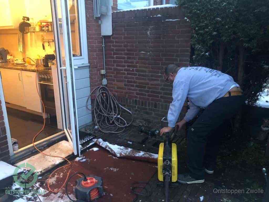 Een monteur werkt buiten bij een open riool-/grondput met een elektrische ontstoppingsmachine om een verborgen afvoerprobleem op te sporen in Zwolle