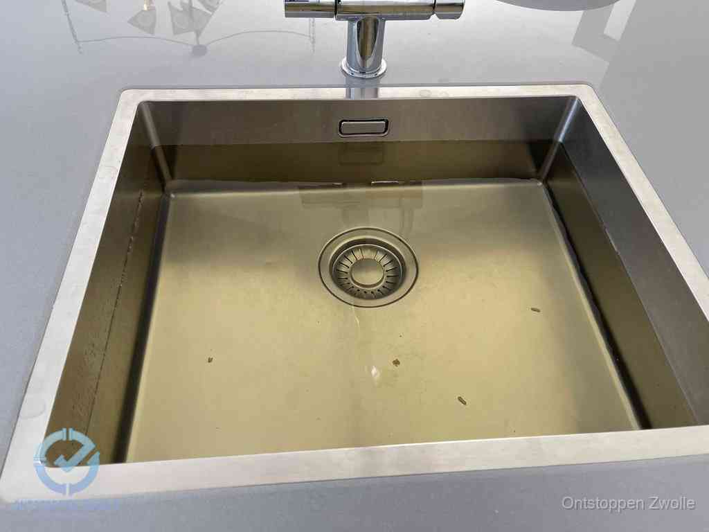 Stilstaand water in een rvs spoelbak dat niet wegloopt, een duidelijk signaal van een gootsteenverstopping in Zwolle
