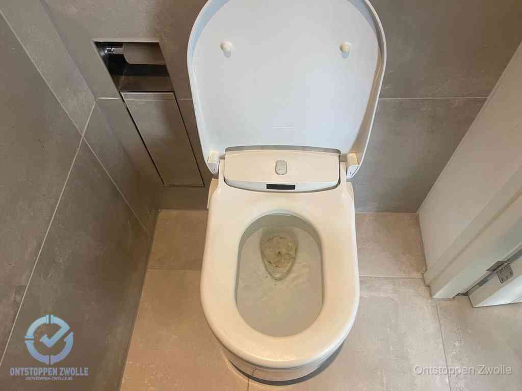 Een wit hangtoilet waarin een prop wc-papier op het water blijft drijven, een duidelijk signaal van een verstopte wc in Zwolle