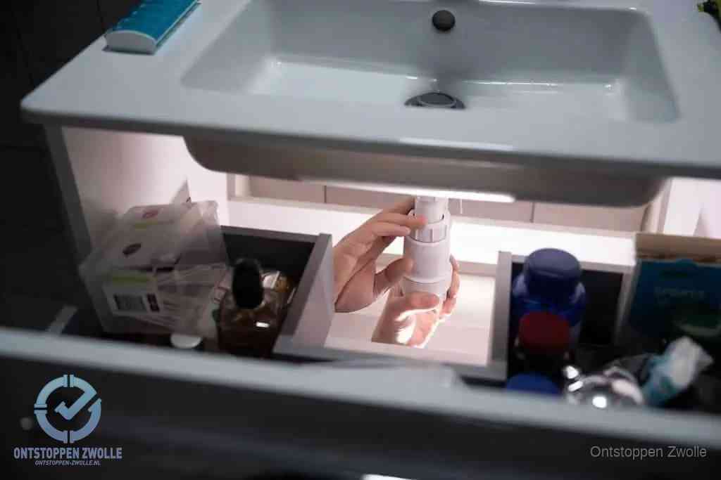 Een pompfles met zeep boven een wastafel in de toiletruimte, de warm water en afwasmiddel-methode om de wc te ontstoppen in Zwolle