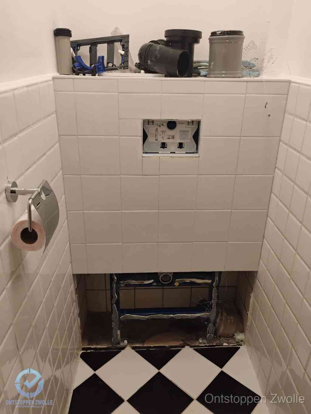 Een toiletruimte waar het hangtoilet en de inbouwreservoir-onderdelen zijn vrijgelegd voor onderhoud, periodiek nazicht voorkomt een wc-verstopping in Zwolle