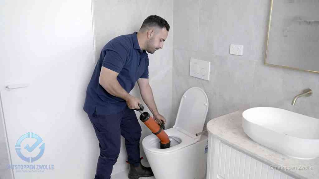 Een monteur gebruikt een handmatige perspomp (toiletontstopper) op een wandcloset tijdens het professioneel wc ontstoppen in Zwolle