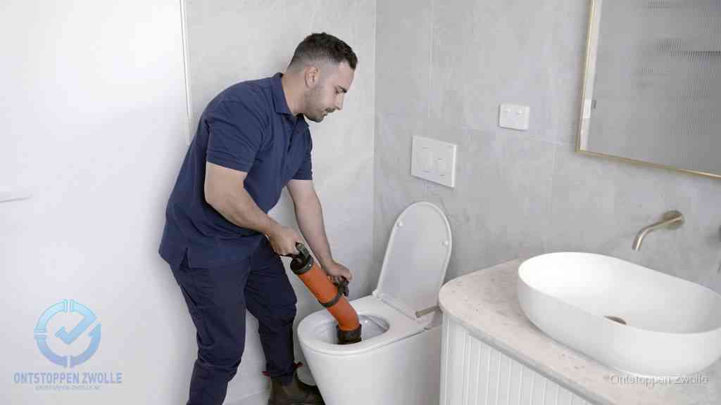 Een man gebruikt een handmatige luchtdruk-ontstopper in een modern betegeld toilet om zelf de wc te ontstoppen in Zwolle